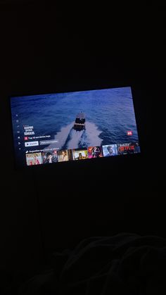 a flat screen tv sitting on top of a bed in a room with dark walls
