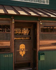 the front door of a restaurant with an advertisement on it's window and sign that says daisy