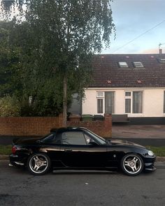 a black sports car parked in front of a house