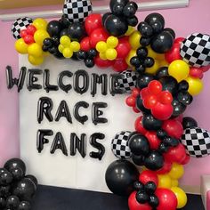 a welcome sign with balloons and streamers in the shape of checkered race cars