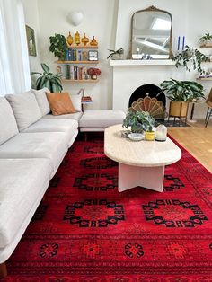 a living room filled with furniture and a red rug on the floor in front of a fire place