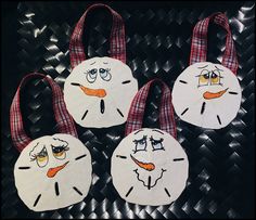 three snowmen made out of toilet paper on top of a black table with red and white checkered ribbon