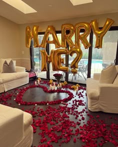 a room with rose petals on the floor and balloons in the shape of letters that say marry