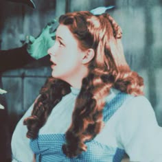 an old photo of a woman with long hair talking to another woman in a blue dress