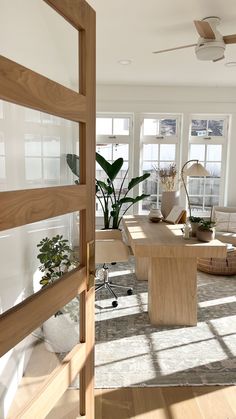 an open living room with lots of windows and plants on the table in front of it