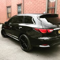 a black car parked in front of a brick building