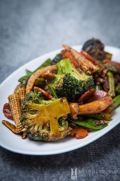 a white plate topped with broccoli and other vegetables
