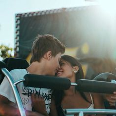 a young man and woman sitting in a chair together, with the sun shining on them