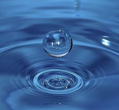 a water droplet is shown in the middle of a blue liquid filled with bubbles