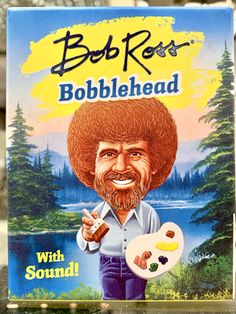 bob ross'bobblehead with sound card game in plastic case on table next to window