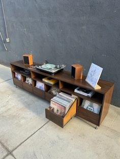 an entertainment center with books, cd's and cds on the shelves in front of a concrete wall