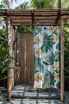an outdoor shower with tropical curtains and palm trees in the backgrouds, next to a bamboo fence