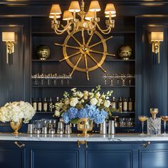 an elegant bar with blue cabinets and gold accents is adorned with white flowers, hydrangeas and champagne glasses