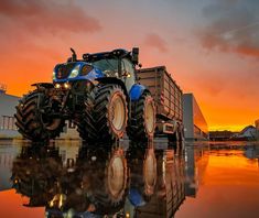 a tractor is parked in front of a building with the sun going down behind it
