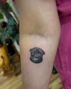 a small black and white pug tattoo on the right thigh, with an outline of a pug