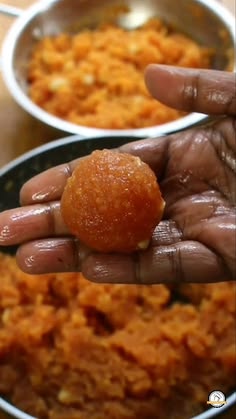 a person holding food in their hand over two bowls filled with oranges and other foods