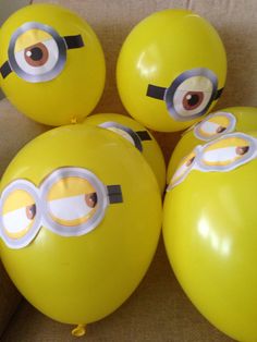 four yellow balloons with minion faces are sitting on the floor next to each other