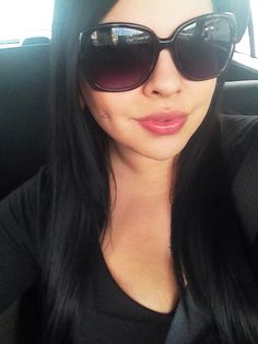 a woman wearing sunglasses in the back seat of a car