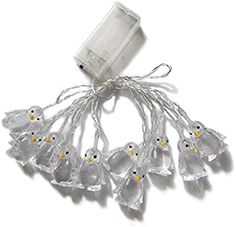 white plastic penguins with yellow eyes are hanging from a string on a white background in the shape of a christmas ornament