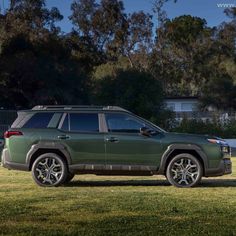 a green suv parked on top of a grass covered field in front of some trees