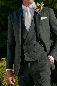 a man in a gray suit and white shirt is standing outside with his hands in his pockets