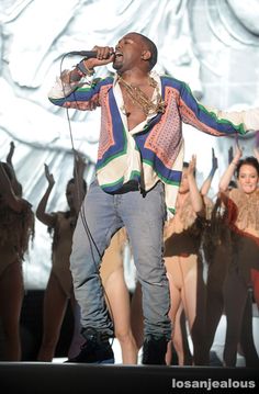 a man standing on top of a stage holding a microphone in front of other people