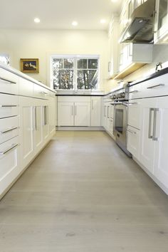 an empty kitchen with white cabinets and stainless steel appliances