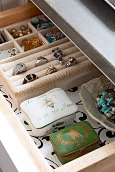 an open drawer filled with lots of rings and bracelets on top of a table