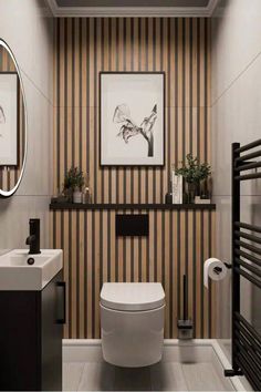 Contemporary bathroom with earthy tones featuring a wall-mounted toilet and a compact sink with a black vanity. The back wall showcases vertical wood slats with black accents, complemented by minimalist black fixtures and a round LED mirror. A black towel radiator and subtle greenery complete the modern, stylish design.