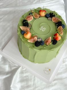 there is a green cake with fruit on it