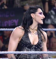 a woman with tattoos on her face standing in front of a roped off ring