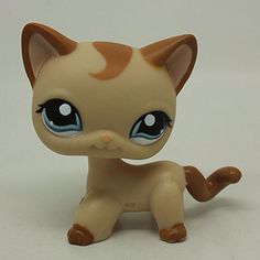 a small toy cat with big blue eyes on a white surface, looking at the camera