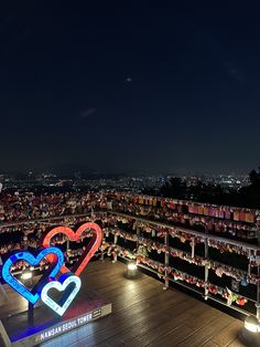 an aerial view of a city at night with lights on the buildings and two heart - shaped signs