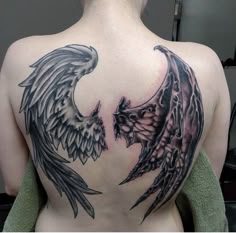 the back of a woman's shoulder with two black and grey wings on it