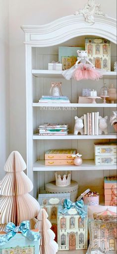 a white bookcase filled with lots of books next to a christmas tree and other items