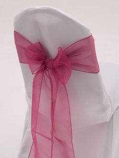 the back of a chair with a pink bow on it's sash and seat cover