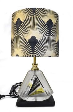 a lamp that is sitting on top of a table with a black base and gold trim