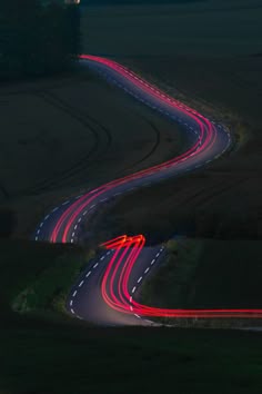 a long exposure photo of a road with red and white lights on it at night