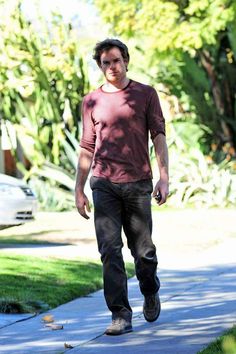 a man is walking down the sidewalk with his hand in his pocket