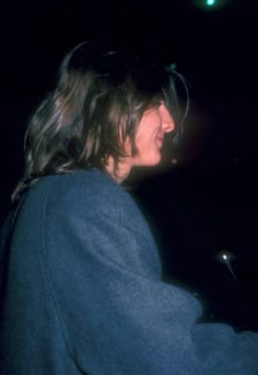 a woman standing in front of a piano and smiling at the camera while wearing a blue sweater