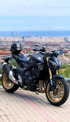 a black motorcycle parked on the side of a road next to a large cityscape