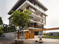 two people are walking their dogs in front of a large building with balconies