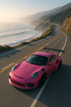 a pink sports car driving down the road next to the ocean with a surfboard on it's roof