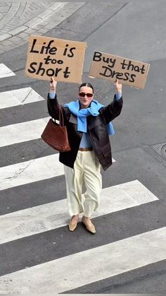 a man holding two signs that say life is short and buy that dress