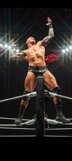 a man standing on top of a wrestling ring holding his hands up in the air