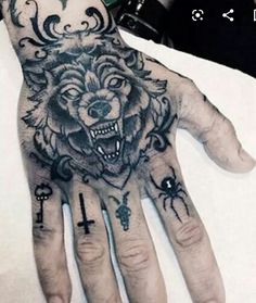 a hand with a wolf and cross tattoo on it