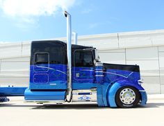 a blue semi truck parked in front of a building