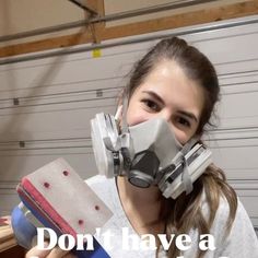 a woman wearing a gas mask and holding a sandpaper in front of her face