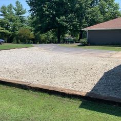 a gravel driveway in front of a house with a car parked on the other side