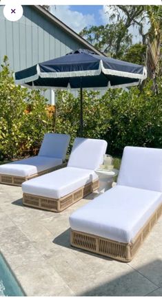 two chaise lounge chairs with an umbrella over them next to a swimming pool in the backyard